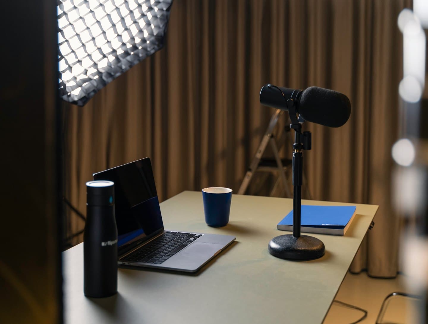Podcast microphone and laptop on a green desk.